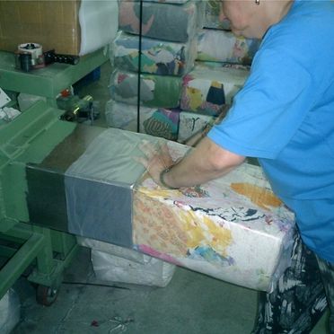 Frau verpackt bunte Stoffe oder Lappen mit Hilfe eines technischen Gerätes